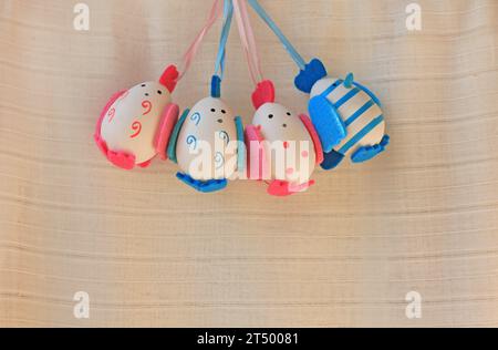 Easter holiday concept with cute handmade eggs, chicks with felt wings, tail and tuft. Funny chickens with stripes and dots. Blue boys eggs and pink g Stock Photo
