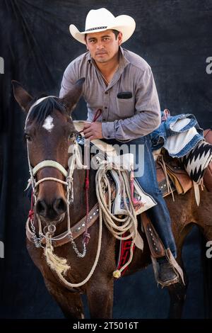 A Mexican cowboy taking part in the annual four-day Cabalgata de Cristo Rey cowboy pilgrimage poses for a portrait on horseback, January 5, 2019 in Salamanca, Guanajuato, Mexico. Thousands of Mexican cowboys and their horses join the religious journey from the high desert villages to the mountaintop shrine of Cristo Rey. Stock Photo