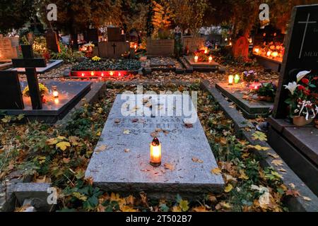 Lit candles stand on graves on All Saints' Day at the Evangelical-Augsburg Cemetery in Warsaw. All Saints' Day (or Dzie? Zaduszny in Polish) is a public holiday in Poland. It is an opportunity to remember deceased relatives. On this day, people bring flowers, typically chrysanthemums, and candles to cemeteries. The entire cemetery is filled with lights in the darkness. The Evangelical-Augsburg Cemetery is a historic Lutheran Protestant cemetery located in the western part of Warsaw. Since its opening in 1792, more than 100,000 people have been buried there. Stock Photo