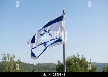 A torn and shredded Israeli flag flutters in the wind at the top of a ...