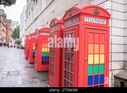 A row of classic K6 red phone boxes decorated with LGBTQ rainbow colours in Broad Court, Covent Garden, London, England, U.K. Stock Photo