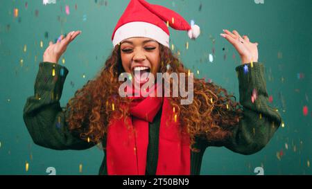 Happy young woman tosses rainbow confetti and dances at Christmas, studio Stock Photo