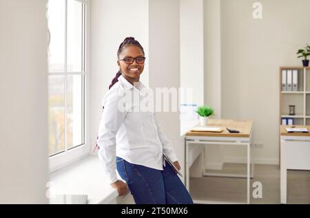 Cheerful young woman standing and looking at camera Stock Photo