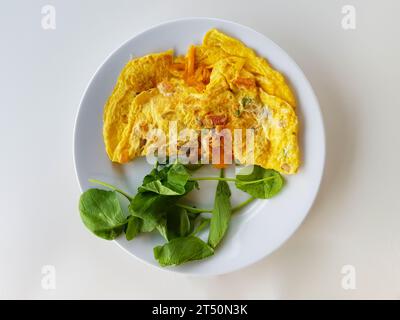 Scrambled eggs with greens on white plate and white table from top view Stock Photo