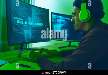 Cyber, gaming and a man with a computer for hacking, streaming music or working on phishing. Serious, dark and a hacker or gamer with a website or Stock Photo