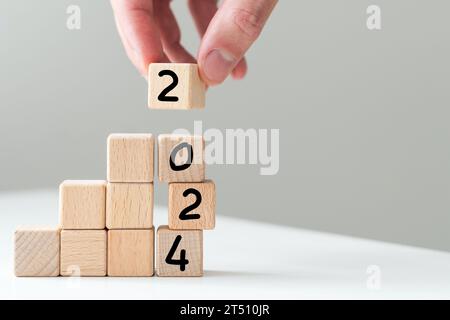 2024 in concept of wooden block numbers. Human hand holding block number isolated on white Stock Photo