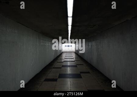 Birmingham, West Midlands, UK: A symmetrical view of a deserted Queensway pedestrian underpass with lighting along the ceiling and a tiled floor. Stock Photo