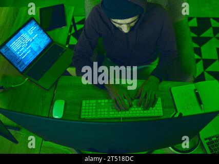 Cybersecurity, crime and man programming from above in neon office with code, fraud and hacking. Software, ransomware and web hacker on cyber attack Stock Photo
