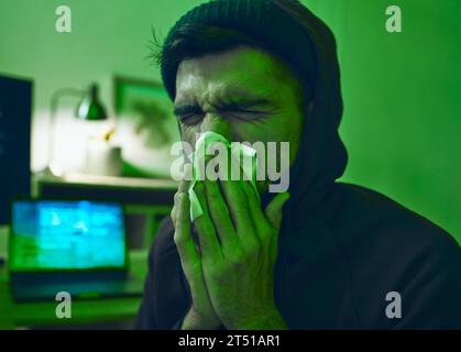 Man, computer or sick hacker with virus in office for code, online fraud or cybersecurity crime at night. Tissue, fever or ill programmer blowing nose Stock Photo