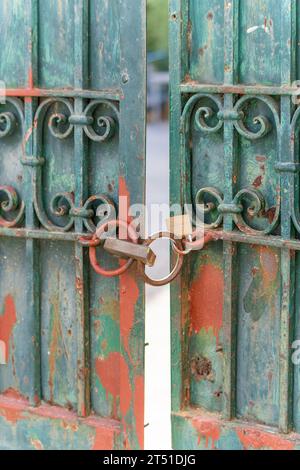 Green rusty ornate metal gates with a padlock Stock Photo