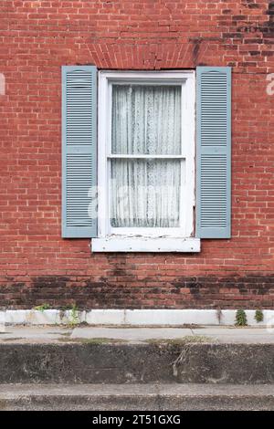 Old window and blue shutters in brick wall Stock Photo