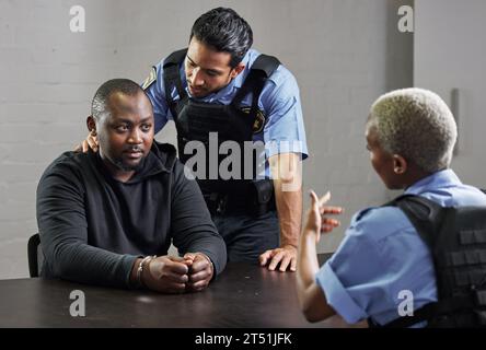 Police, criminal and handcuffs for interrogation, arrest or justice in fraud, scam or crime. Law enforcement officers talking to prisoner, gangster or Stock Photo