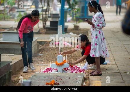 New Delhi, India. 02nd Nov, 2023. Children seen lighting candles on the grave of their relative during the All souls day observation at Delhi Cantonment Christian Cemetery. All Souls' Day on November 2nd is a Christian tradition to pray for departed souls, especially those in Purgatory, through church services, prayers, and cemetery visits, with the hope of their ultimate salvation. Credit: SOPA Images Limited/Alamy Live News Stock Photo