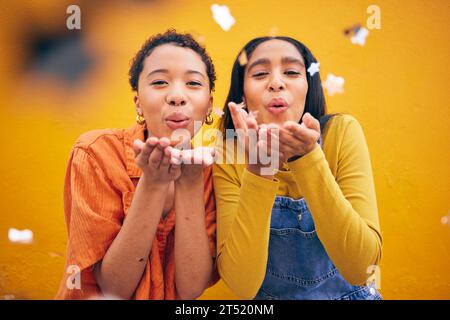 Blowing, petals and women friends on orange background for natural beauty, skincare and romance. Flowers, happy and female people with floral confetti Stock Photo