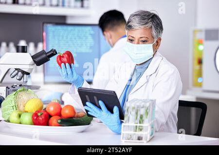 Female scientist, vegetables and lab with tablet for information on app or research for diet. Science, expert and study with technology for food or Stock Photo