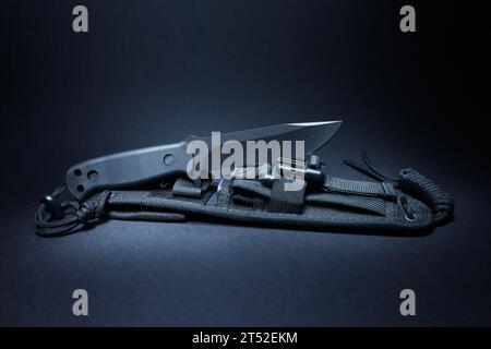 Outdoor, survival knife with fixed blade and knife sheath on a black background. Stock Photo