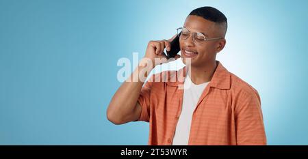 Phone call, mockup space or happy man in studio on blue background talking for communication. Modern, trendy or cool biracial model listening or Stock Photo