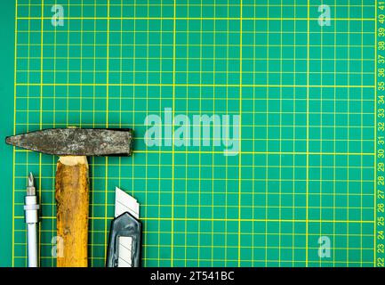 screwdriver hammer and knife isolated on green cutting mat Stock Photo