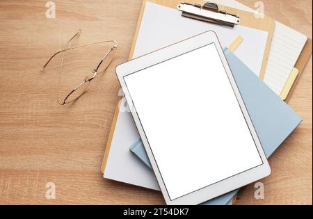 Tablet empty white screen and notebooks  on the office desk Stock Photo