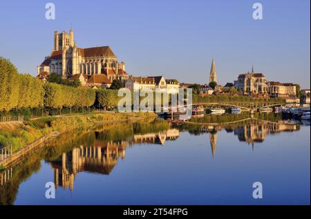 Auxerre: Cathedral Saint Etienne, Abbey Saint-Germain and boats glowing gold soon after sunrise with mirror reflections in River Yonne, Burgundy Stock Photo