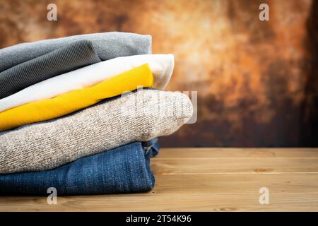 Stack of folded clothes on a wooden background. Stock Photo