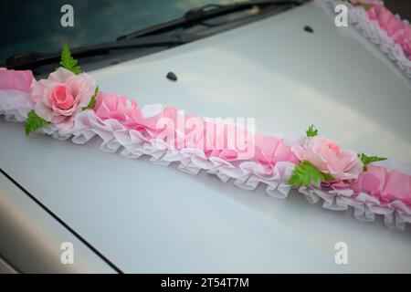 Tape on the car. Wedding decoration on transport. Pink ribbon on the hood. Decorated Machine. Stock Photo