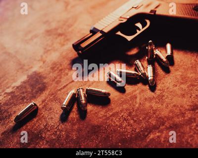 Hand gun with ammunition on dark background. 9 mm pistol military weapon and pile of bullets ammo at the metal table. Stock Photo