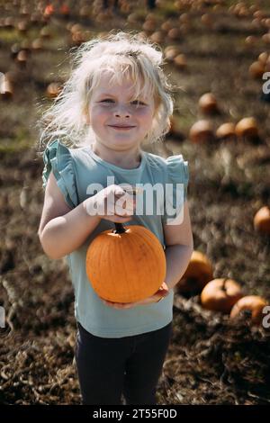 Smiling girl holding pumpkin at pumpkin patch Stock Photo