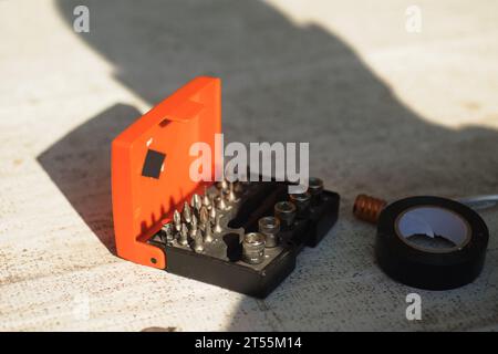 a box with tools, a box with a screwdriver and bits, and electrical tape nearby Stock Photo