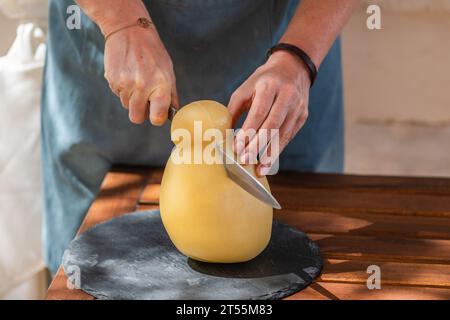 female hand's cutting a caciocavallo silano cheese on a cutting board Stock Photo