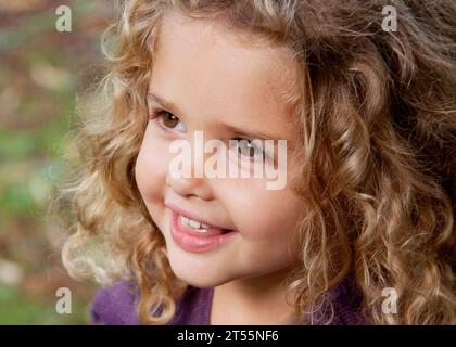 portrait of pretty healthy looking toddler girl in the park with a blurred out autumnal background Stock Photo