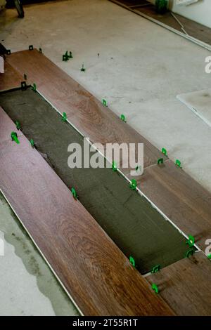 Tile levelling system, four plastic green clips with wedges. Close-up view, selective focus, blurred background. Stock Photo