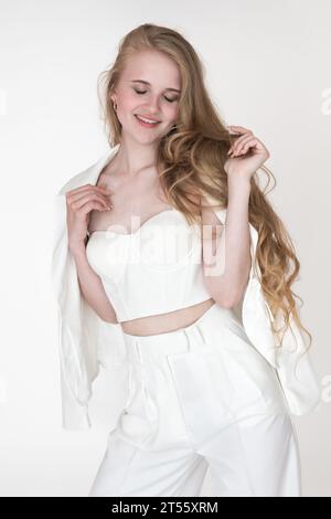 Portrait of happy smiling young woman with closed eyes. Fashionable Caucasian woman with blonde long wavy hair well dressed Stock Photo