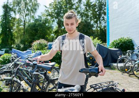 Guy college student with backpack with bike, educational building background Stock Photo