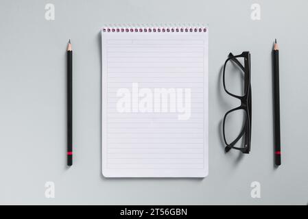 Top view of empty notebook, glasses and pen on grey office desk Stock Photo
