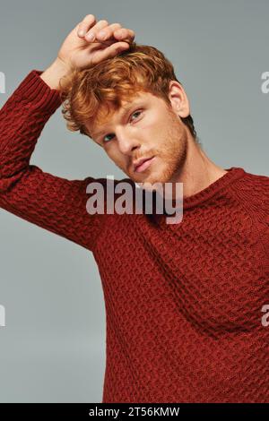 portrait of young red haired man in red comfy sweater posing and looking at camera, fashion Stock Photo