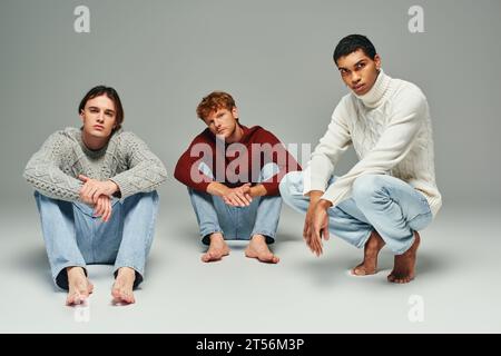 good looking interracial men in casual outfits posing on floor and looking at camera, fashion Stock Photo