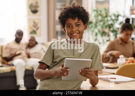 Portrait of cheerful Black boy with tablet computer spending weekend at home Stock Photo
