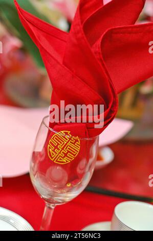 A napkin with Chinese character tucked into a wine glass; an art form in hotel banquet. Symbol of marriage. Stock Photo