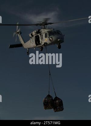 US Navy An MH-60S Sea Hawk helicopter assigned to Helicopter Anti-Submarine Squadron (HSC) 23 delivers supplies to the flight de.jpg Stock Photo