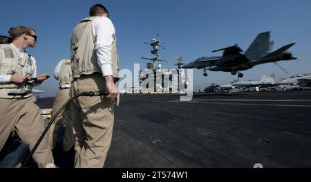 US Navy Landing signal officers observe as an F18C Hornet from the Warhawks of Strike Fighter Squadron (VFA) 97 lands on the.jpg Stock Photo