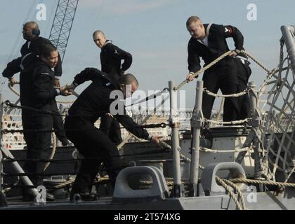US Navy Line handlers aboard the guided-missile frigate USS Nicholas (FFG 47) pull up the mooring lines as the ship prepares to.jpg Stock Photo