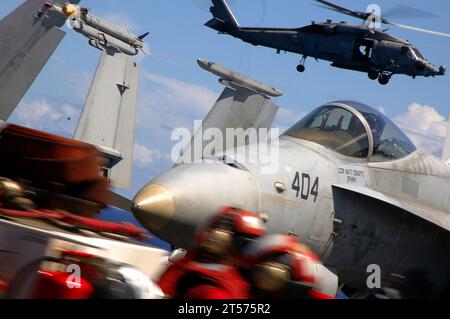 US Navy Members of the crash and salvage crew aboard the aircraft carrier USS Kitty Hawk drive across the flight deck as a Helicopter Anti-Submarine Squadron (HS) 14 aircraft lands in the background.jpg Stock Photo