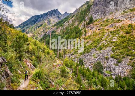 Woman hiking Snow Lakes Trail, Snow Creek Wall on right, Edward Peak in dist, Alpine Lakes Wilderness, Wenatchee Mtns, Cascade Range, Washington, USA Stock Photo