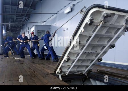 US Navy Sailors assigned to the engineering repair division aboard the amphibious command ship USS Blue Ridge (LCC 19) raise an external hatch to perform maintenance on the watertight gasket and moving parts.jpg Stock Photo