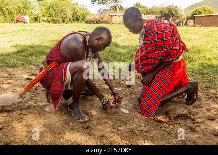 MASAI MARA, KENYA - FEBRUARY 20, 2020: Masai men making a fire in their village, Kenya Stock Photo