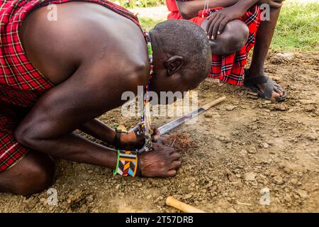 MASAI MARA, KENYA - FEBRUARY 20, 2020: Masai men making a fire in their village, Kenya Stock Photo