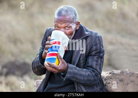 african man drinking commercially available packed kadi traditional beer made of wild berries, Grewia flava fruits, sorghum and maize, village in Bots Stock Photo