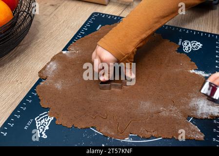 A child cutting out various shapes of gingerbread from raw dough using shapes. Stock Photo