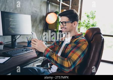 Profile side photo of clever freelancer product manager in it company answer colleagues email using smartphone near pc indoors office Stock Photo